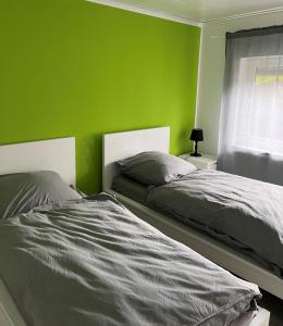 two beds in a bedroom with a green wall at Hannis-Hof in Meinerzhagen