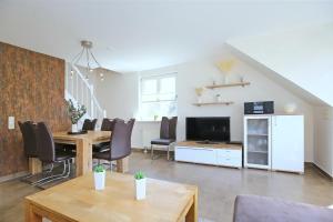 a living room with a table and chairs and a television at Papillon Wohnung 04-5 in Boltenhagen