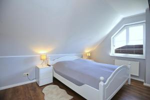 a white bedroom with a white bed and a window at Papillon Wohnung 04-5 in Boltenhagen