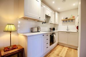 eine weiße Küche mit weißen Schränken und einer Lampe in der Unterkunft 14th century Rose cottage, Centre of Alfriston By Air Premier in Alfriston
