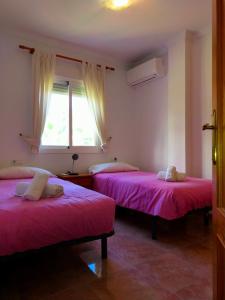 2 camas en una habitación con sábanas rosas y ventana en Nerja Sun Apartments Casa Cipreses 6, en Nerja 21 fotos más