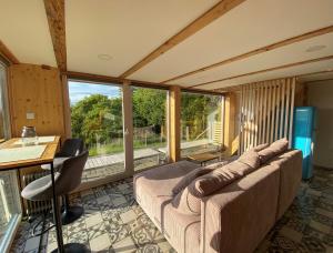 a living room with a couch and a table and windows at Wellness hiška Robida in Ljutomer