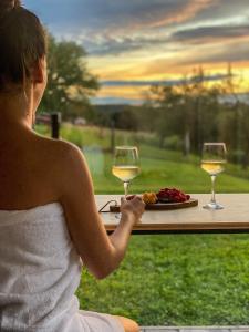 uma mulher sentada à mesa com dois copos de vinho em Wellness hiška Robida em Ljutomer