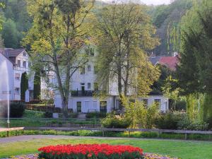 ein weißes Haus mit Blumen im Garten in der Unterkunft Parkhotel Am Schwanenteich in Bad Sooden-Allendorf