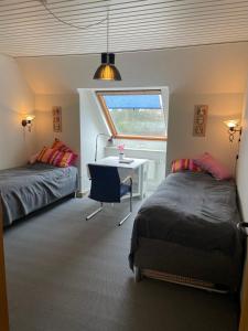 1 dormitorio con 2 camas, escritorio y ventana en Lejlighed med egen indgang midt i Nykøbing Falster, en Nykøbing Falster