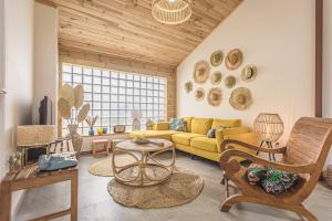una sala de estar con sofá amarillo y techos de madera. en Maison créole traditionnelle au coeur de la Rivière, en Saint-Louis