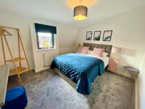 a bedroom with a bed with a blue blanket and a window at Minster Peek With Free Parking in York