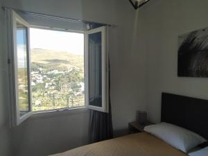 a bedroom with a bed and a large window at Πλατανακι 1 Family Friendly in Andros