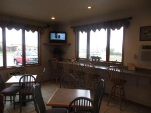 a dining room with tables and chairs and windows at Super 8 by Wyndham Spearfish in Spearfish