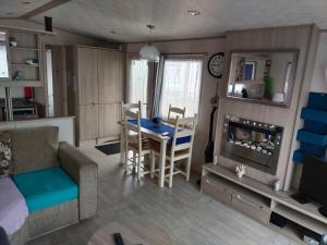 a living room with a couch and a table in a room at MOBIL HOME LE MAGNIFIQUE VALRAS PLAGE in Valras-Plage
