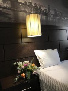 a bedroom with a bed and a lamp and flowers at Hotel Kardinal in Blagoevgrad