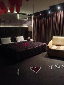 a bedroom with a bed and a couch and red balloons at Hotel Kardinal in Blagoevgrad