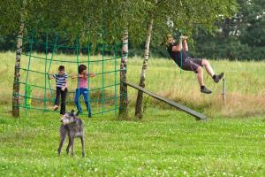 a woman and two children and a dog playing on a net at Domek w górach in Międzylesie