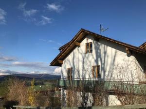 Biały dom z drewnianym dachem i cieniem w obiekcie Ferienwohnungen Lusenblick w mieście Freyung