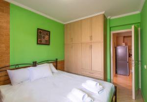 ein grünes Schlafzimmer mit einem Bett mit Handtüchern darauf in der Unterkunft Franceska's guest house in Artemida