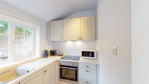 a kitchen with white cabinets and a sink and a microwave at Hidden Jewel Retreat in Budleigh Salterton