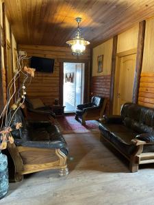 a living room with leather furniture and a chandelier at Kurėnų Užeigos Svečių Namai in Kurėnai