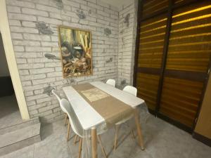 a dining room table with white chairs and a painting on a brick wall at Adi in Arad