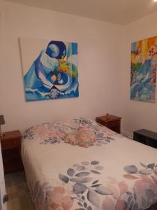 een slaapkamer met een bed en een schilderij aan de muur bij La chambre de Garance et ses couleurs d'art in Saint-Pol-de-Léon