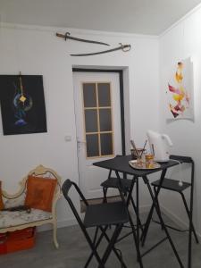 uma sala de jantar com uma mesa, cadeiras e uma cadeira em La chambre de Garance et ses couleurs d'art em Saint-Pol-de-Léon