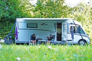 two people sitting in front of a caravan at Lege Kampeerplaats + Prive Sanitair, Camping Alkenhaer in Appelscha