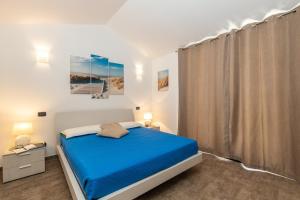 Un dormitorio con una cama azul y una ventana. en APPARTAMENTI GAIMARO' a 50 m dalla spiaggia, en Àrbatax