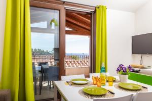 une salle à manger avec une table et des rideaux verts dans l'établissement APPARTAMENTI GAIMARO' a 50 m dalla spiaggia, à Àrbatax