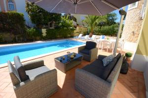 a patio with chairs and an umbrella next to a swimming pool at Casa Da Torre Espetacular V4 Com Piscina in Portimão