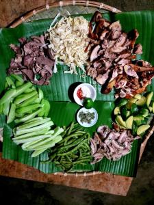 a plate of food with meat and vegetables on a banana leaf at Minh Khang Homestay - Làng đá cổ Khuổi Ky in Cao Bằng