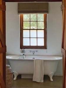 een badkuip in een badkamer met een raam bij Penhill Farm Peppertree Cottage in Nuy