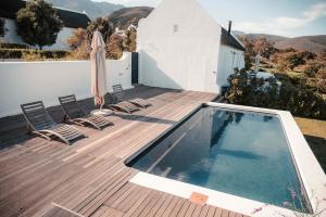 a swimming pool on a deck with chairs and an umbrella at Penhill Farm Fruit Barn in Nuy