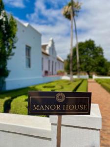 Un cartel que indica una casa señorial frente a una casa. en Penhill Farm The Manor House, en Nuy
