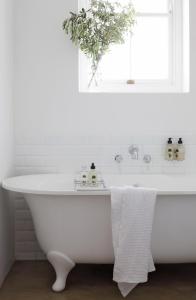 baño con bañera blanca y ventana en Penhill Farm East Grange, en Nuy