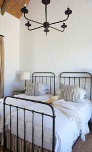 1 dormitorio con 2 camas con sábanas blancas y lámpara de araña en Penhill Farm East Grange, en Nuy