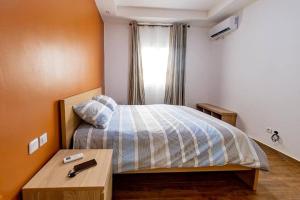 a bedroom with a bed with a table and a window at Douala-Bonapriso: Superbe Appartement in Douala