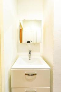 a white bathroom with a sink and a mirror at Douala-Bonapriso: Superbe Appartement in Douala