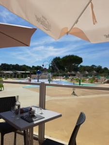 a table with an umbrella in front of a pool at La Palmyre - Les Mathes - Mobil home 3 ch de 40m2 - Grand emplacement dans village loisirs 4 étoiles - "les Charmettes" Les Mathes in Les Mathes