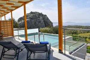 einen Balkon mit Stühlen und einem Pool in der Unterkunft Vrachos luxury home in Agia Galini