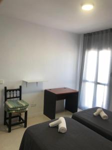 een slaapkamer met 2 bedden, een bureau en een stoel bij Hostal Santa Calma in Marbella