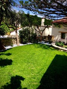 a yard with a green lawn with trees and a house at Chorio House Platanias in Vrísai