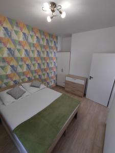 a bedroom with a large bed and a colorful wall at Apartament Białowieski in Hajnówka