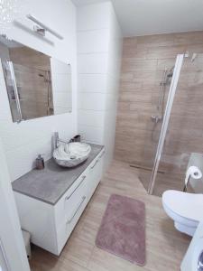 a white bathroom with a sink and a shower at Apartament Białowieski in Hajnówka