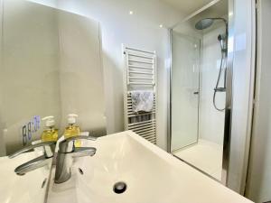 a white bathroom with a sink and a shower at APPART HOTEL DU BOIS DE VINCENNES in Fontenay-sous-Bois