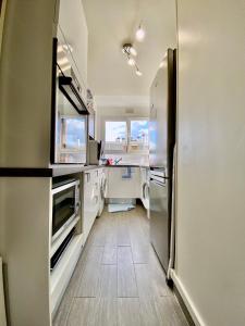 La cuisine est équipée de comptoirs blancs et d'un réfrigérateur. dans l'établissement APPART HOTEL DU BOIS DE VINCENNES, à Fontenay-sous-Bois