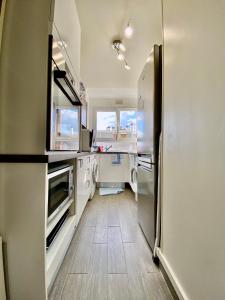 a kitchen with white counters and a refrigerator at APPART HOTEL DU BOIS DE VINCENNES in Fontenay-sous-Bois