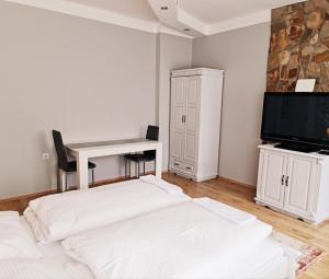Habitación blanca con escritorio y TV. en Hürrem Apartman en Eger