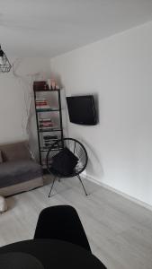 a living room with a chair and a tv on a wall at Apartament Port in Ostróda