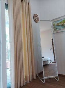 a mirror in a room with curtains and a clock at sofia's cozy rooms in Himare