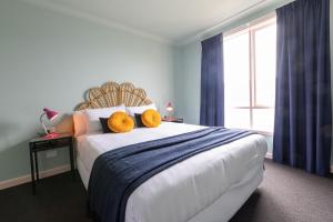 a bedroom with a large bed with two yellow pillows on it at Roamer St Kilda - formerly Selina St Kilda Melbourne in Melbourne