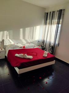 una camera da letto con un grande letto con lenzuola rosse e asciugamani di B&B Etna's Tourist a Catania